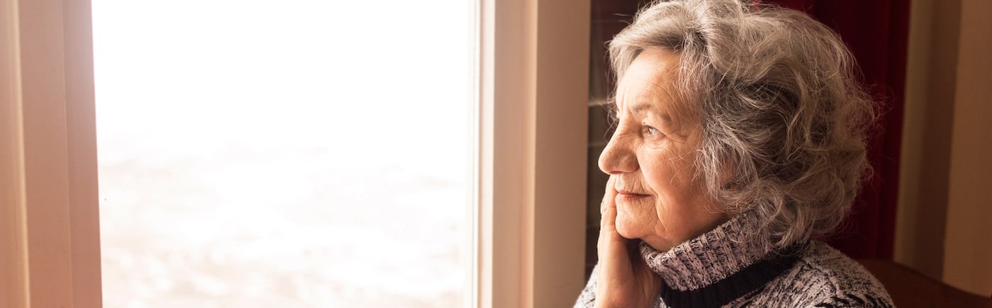 elderly woman looking out of a window